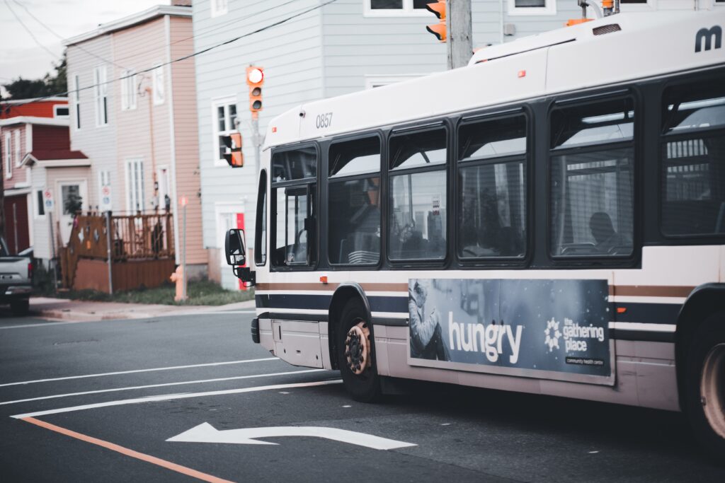 City bus making a turn at an urban intersection with traffic lights and residential buildings.