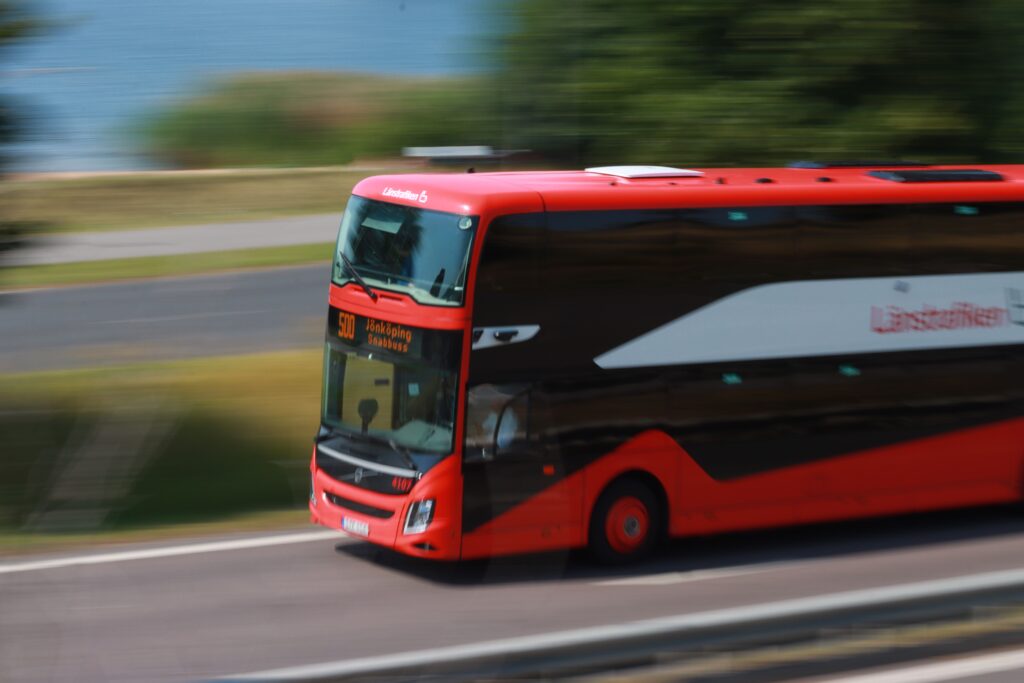 Dynamic panning shot of a red bus moving swiftly through Jönköping, Sweden.
