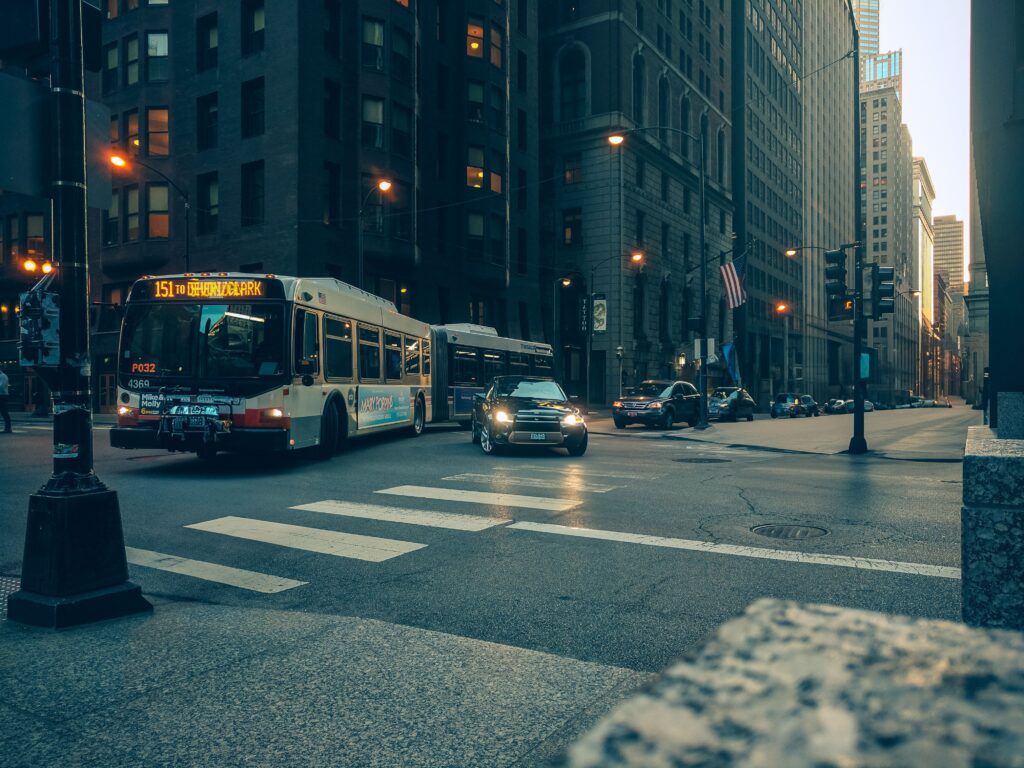 City bus and cars navigate a downtown intersection at twilight, urban USA setting.