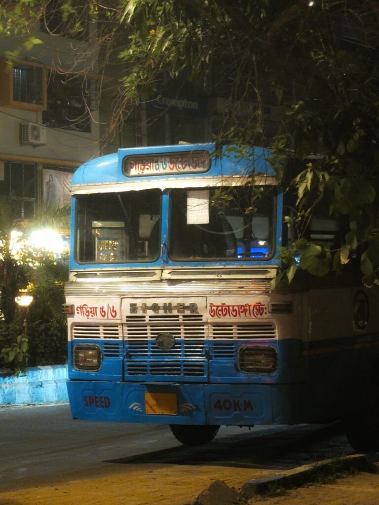 Night scene of a classic blue bus parked on a city street, showcasing urban night life.
